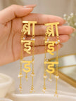 Close-up of both gold Hindi script bride earrings held in an open palm showing cascading chain and pearl bead detail