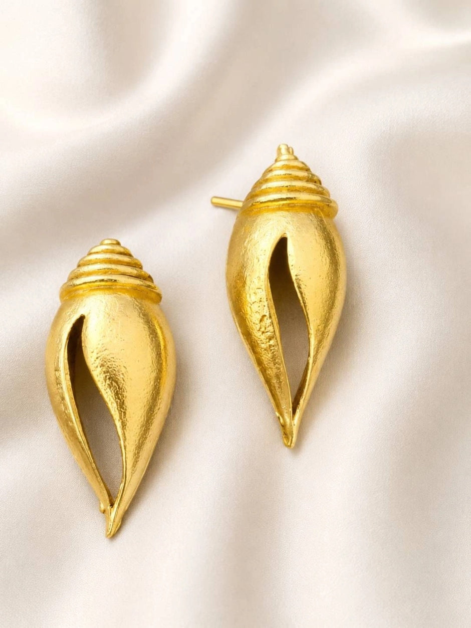 Pair of gold-plated conch shell stud earrings displayed upright on white satin fabric