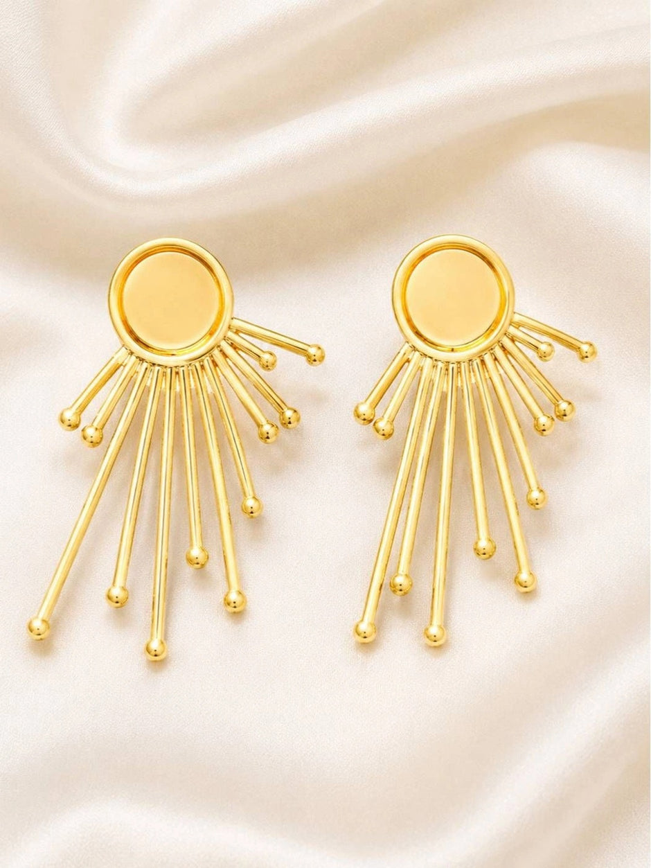 Pair of gold-plated sunburst stud earrings with fanned rays and ball tips on white satin