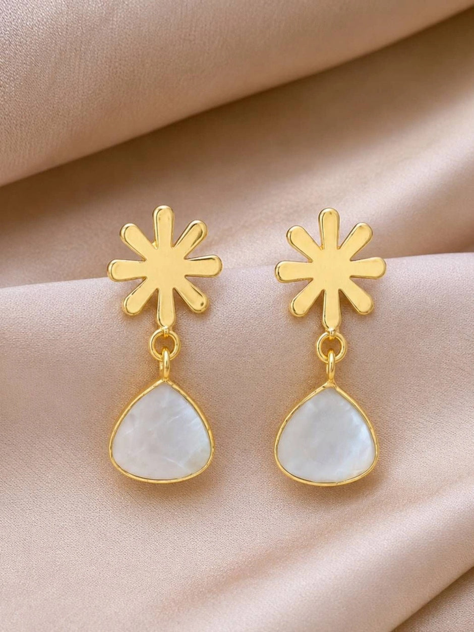 Pair of gold-plated snowflake stud drop earrings with milky white teardrop pendants on a peach satin background