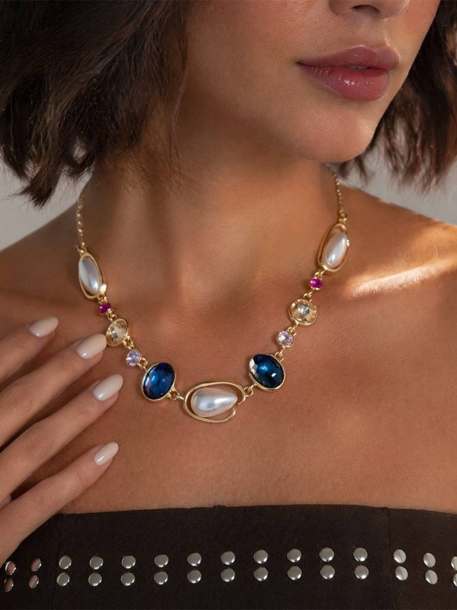 Model wearing pearl and blue crystal gold-toned necklace with a black strapless top