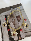 Gold-tone bee and ladybug necklace laid flat on a fashion magazine editorial background