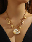 Model wearing gold-plated ocean charm necklace against a black top showing how it sits at the collarbone