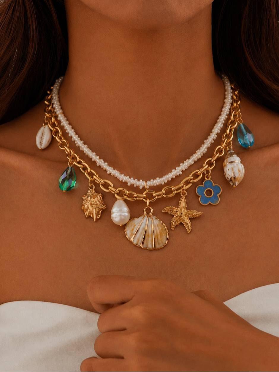 Gold-toned layered shell and starfish charm necklace worn around a woman's neck with a white top