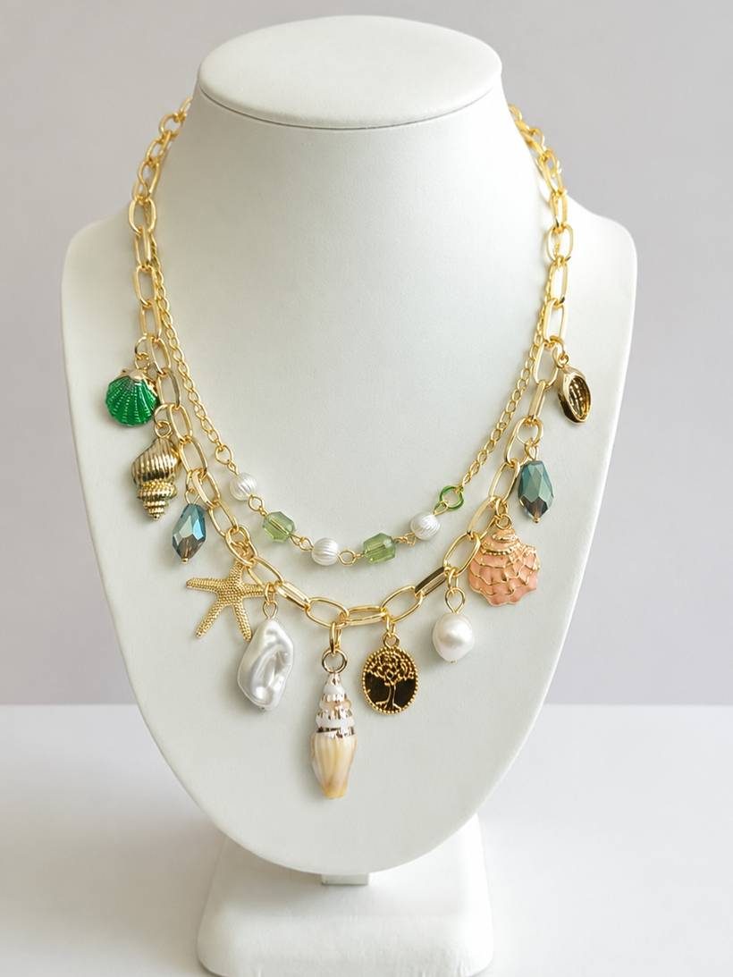 Gold-plated two-strand seashell charm necklace displayed on a white jewellery bust with shell and pearl pendants