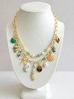 Gold-plated two-strand seashell charm necklace displayed on a white jewellery bust with shell and pearl pendants