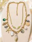 Gold-plated layered seashell necklace on cream jewellery display showing lobster clasp and extension chain