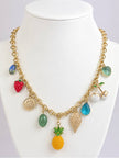 Gold-toned fruit charm necklace displayed on a white jewellery bust showing all charms including pineapple, strawberry and cherries
