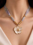 Gold shell flower pendant choker necklace worn on a model with a white off-shoulder outfit