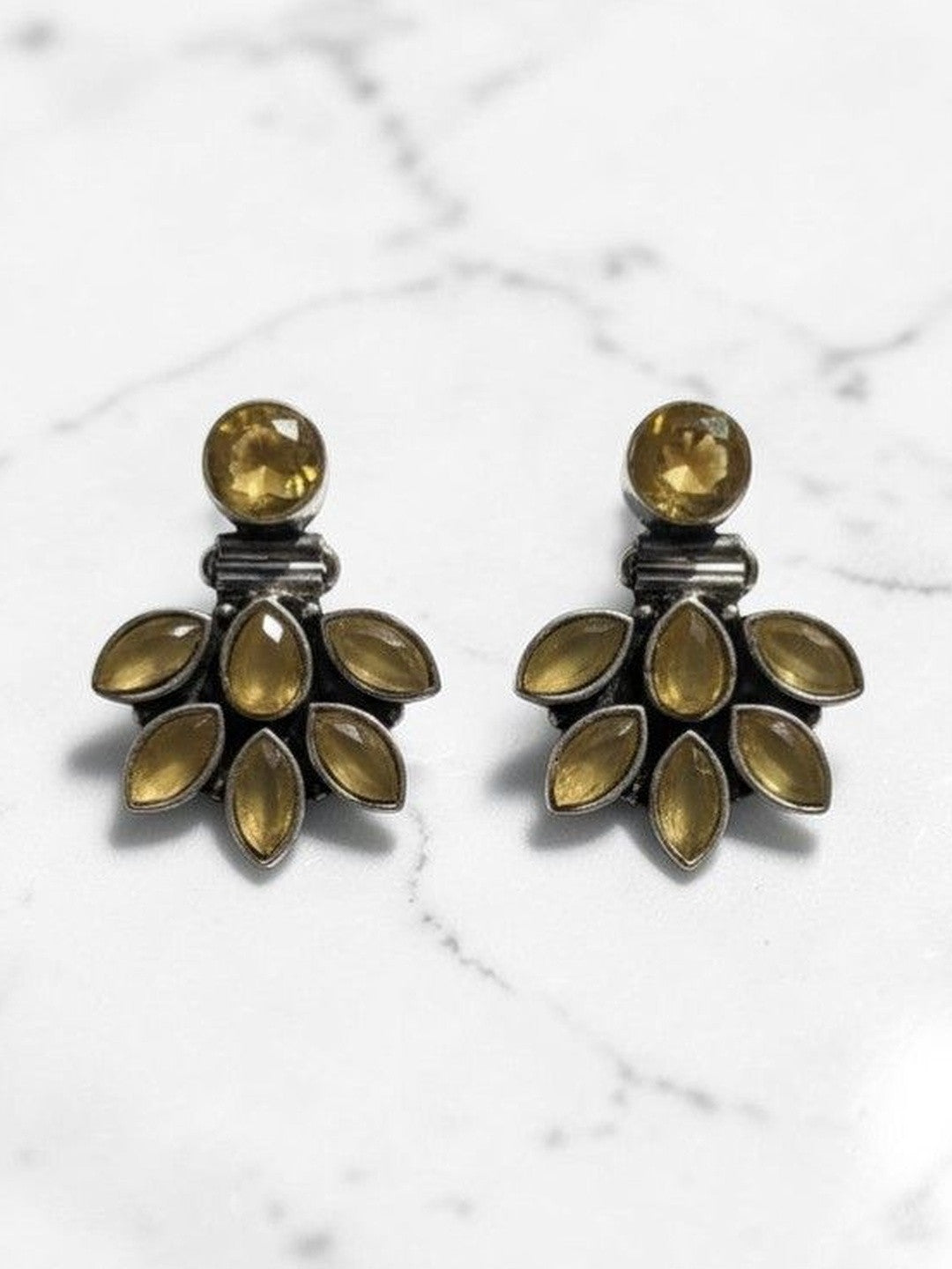 Pair of oxidised silver ear jacket studs with yellow marquise stones on a white marble surface