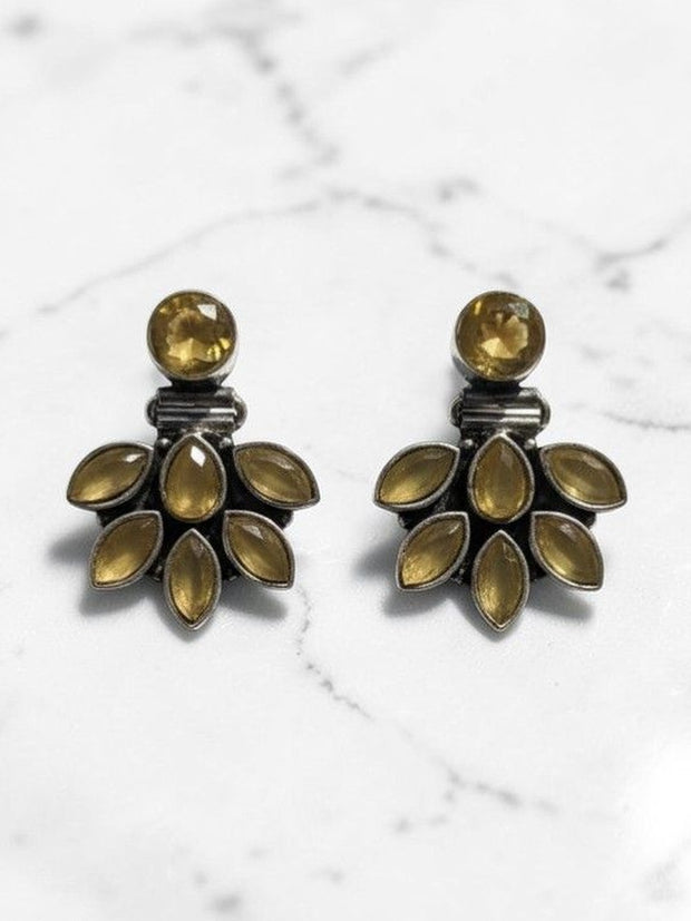 Pair of oxidised silver ear jacket studs with yellow marquise stones on a white marble surface