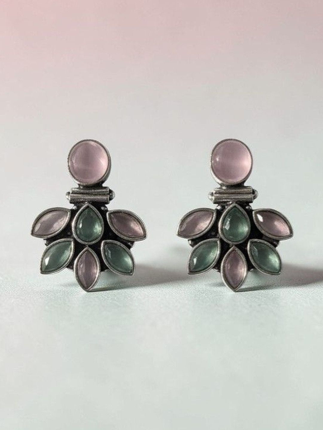 Front-facing pair of oxidised silver earrings with pink and jade-tone stones on light grey background