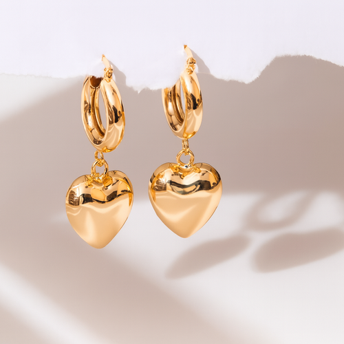 Gold heart-shaped earrings on a light background