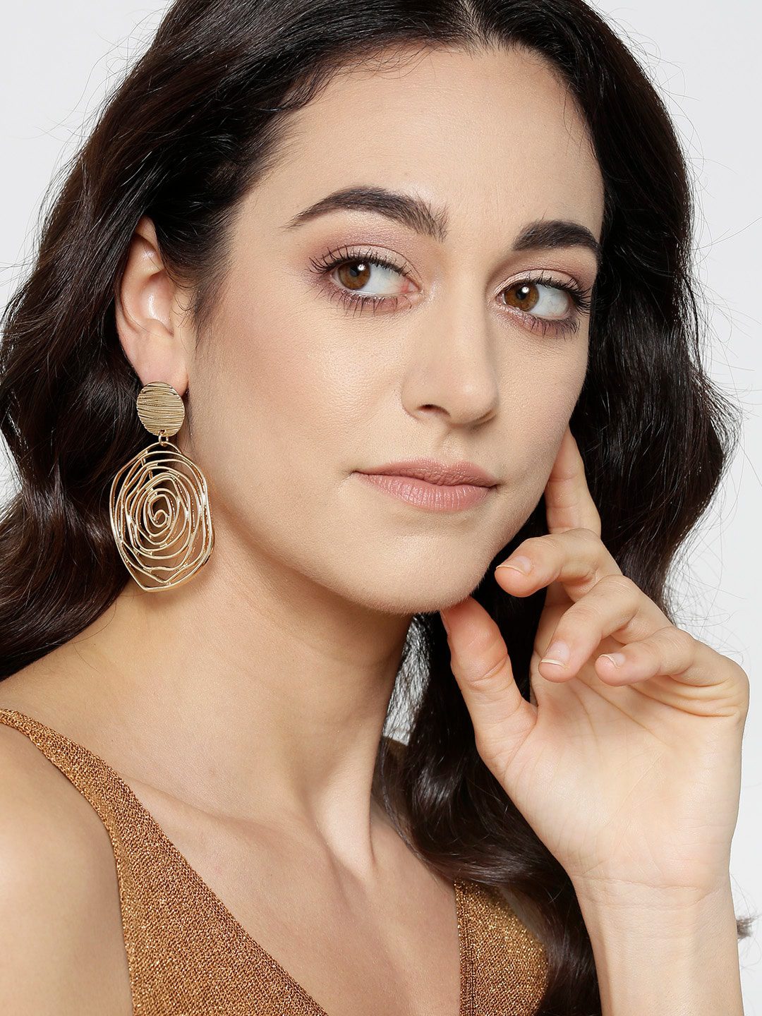 Woman wearing gold earrings with a plain background