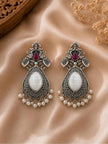 Pair of oxidised silver elephant chandbali earrings with white stone and pearl drops on satin fabric