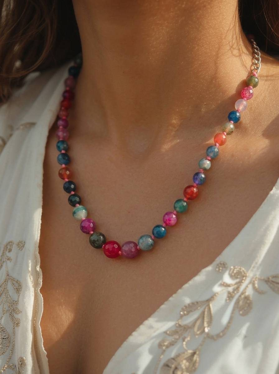 Multicolour agate bead necklace worn around the neck of a woman in a white embroidered top