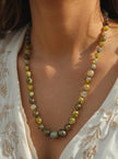 Dragon vein agate necklace worn on a woman's neckline over a white embroidered top in sunlight