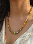 Multicolour agate bead necklace worn on a woman's neck over an ivory embroidered top