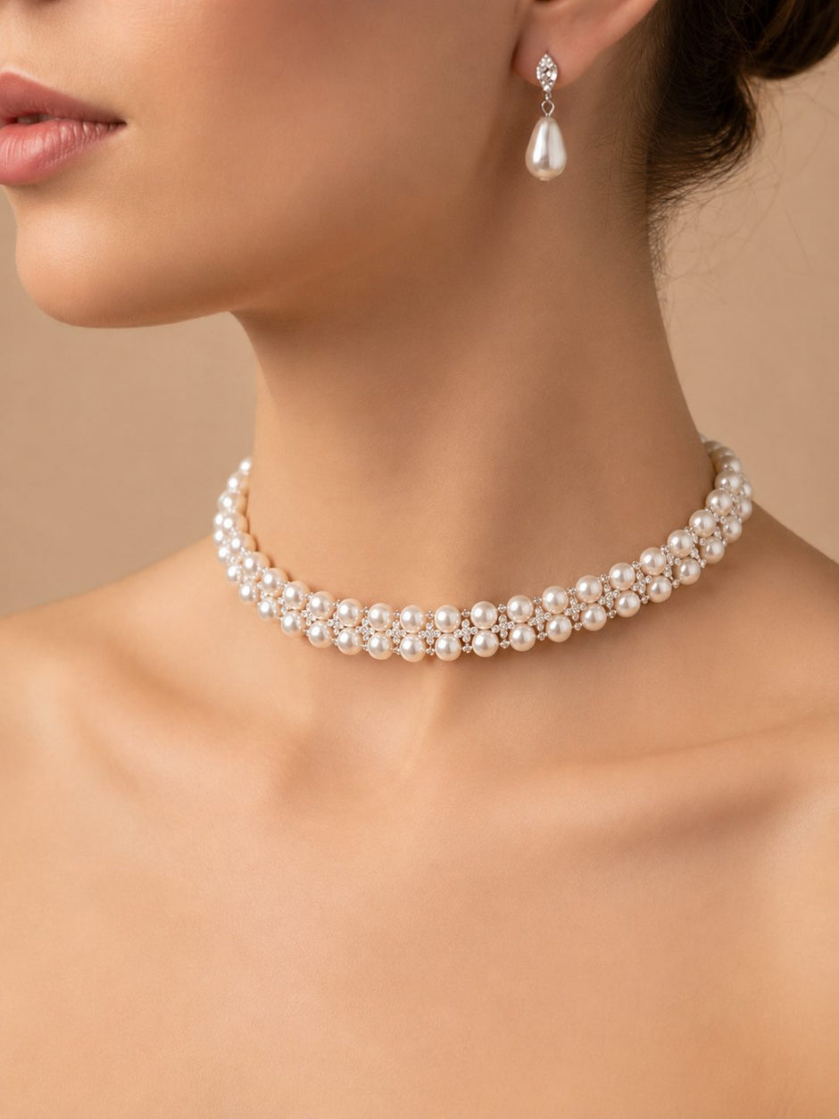 Close-up of model wearing ivory pearl choker necklace with matching teardrop pearl drop earrings