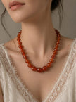 Carnelian agate bead necklace worn on a model with a white lace top showing collarbone placement