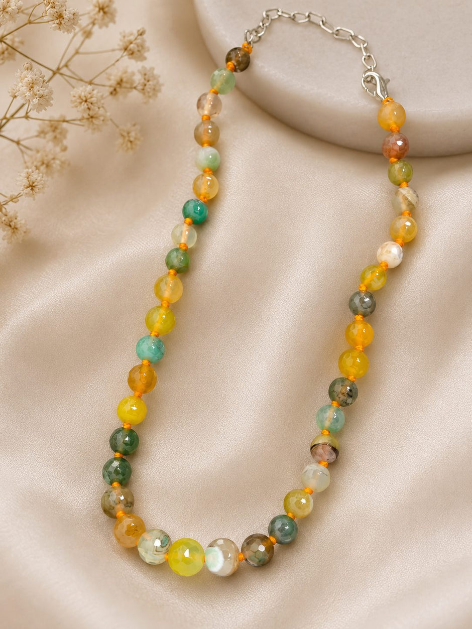 Multicolour agate bead necklace laid on cream satin with dried flowers nearby