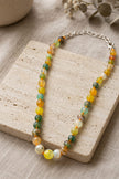Multicolour beaded necklace displayed on a textured travertine stone tile