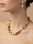 Close side view of woman wearing multicolour bead necklace with pearl drop earrings