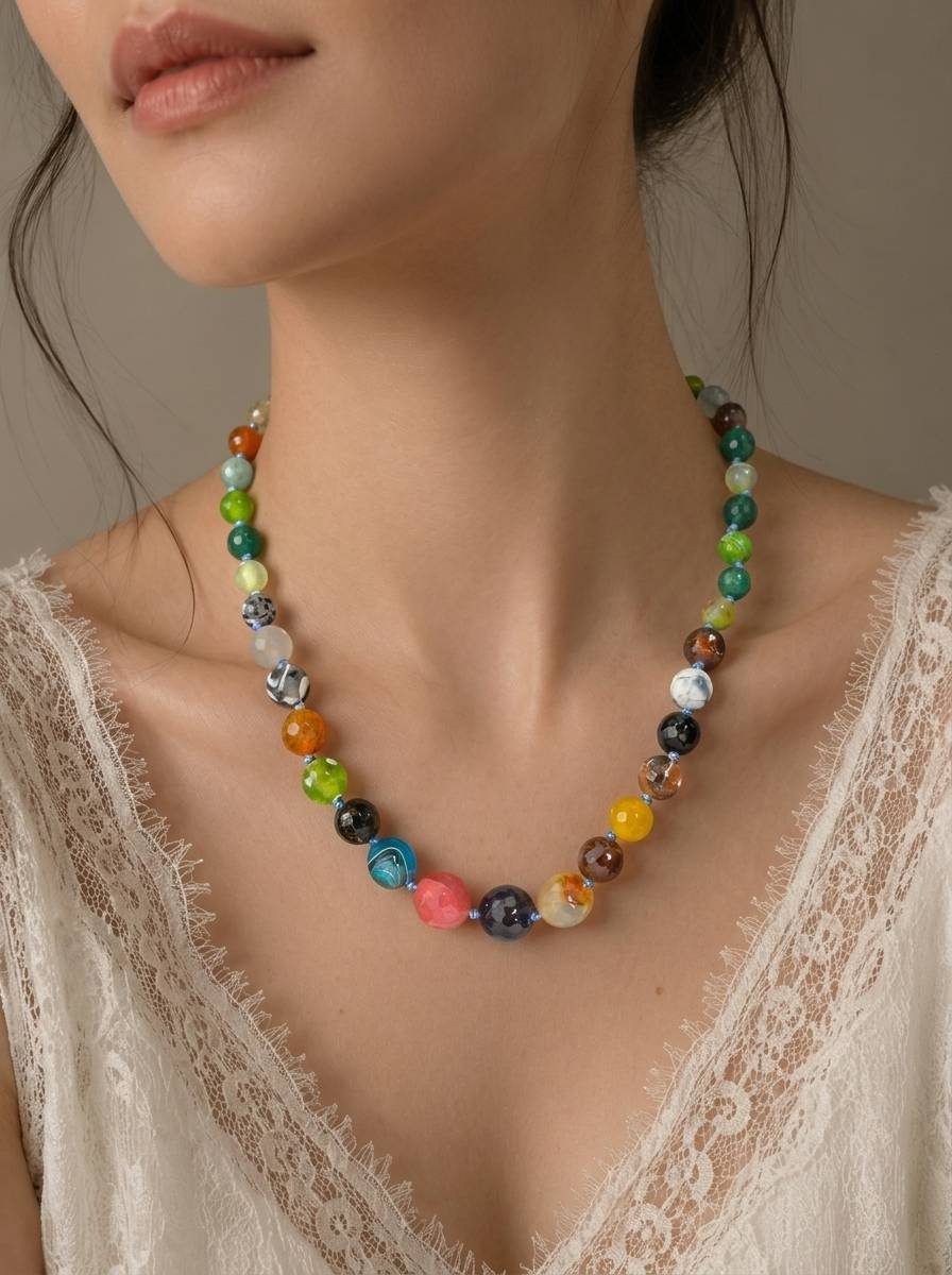 Close-up of multicolour stone bead necklace worn by model over white lace neckline showing bead detail