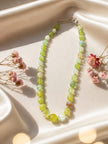 Gradient green agate necklace displayed on ivory satin cloth surrounded by pink dried blooms
