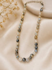 Grey agate-style graduated bead necklace with silver extension chain laid on cream satin with gypsophila