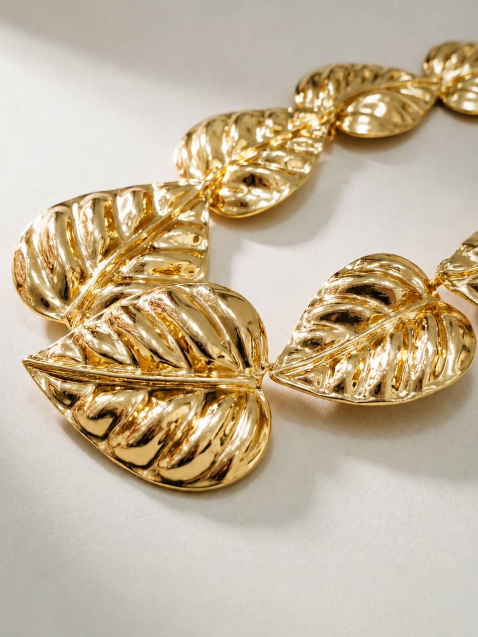 Close-up of three large gold-plated monstera leaf links showing high-shine mirror polish and textured vein detailing