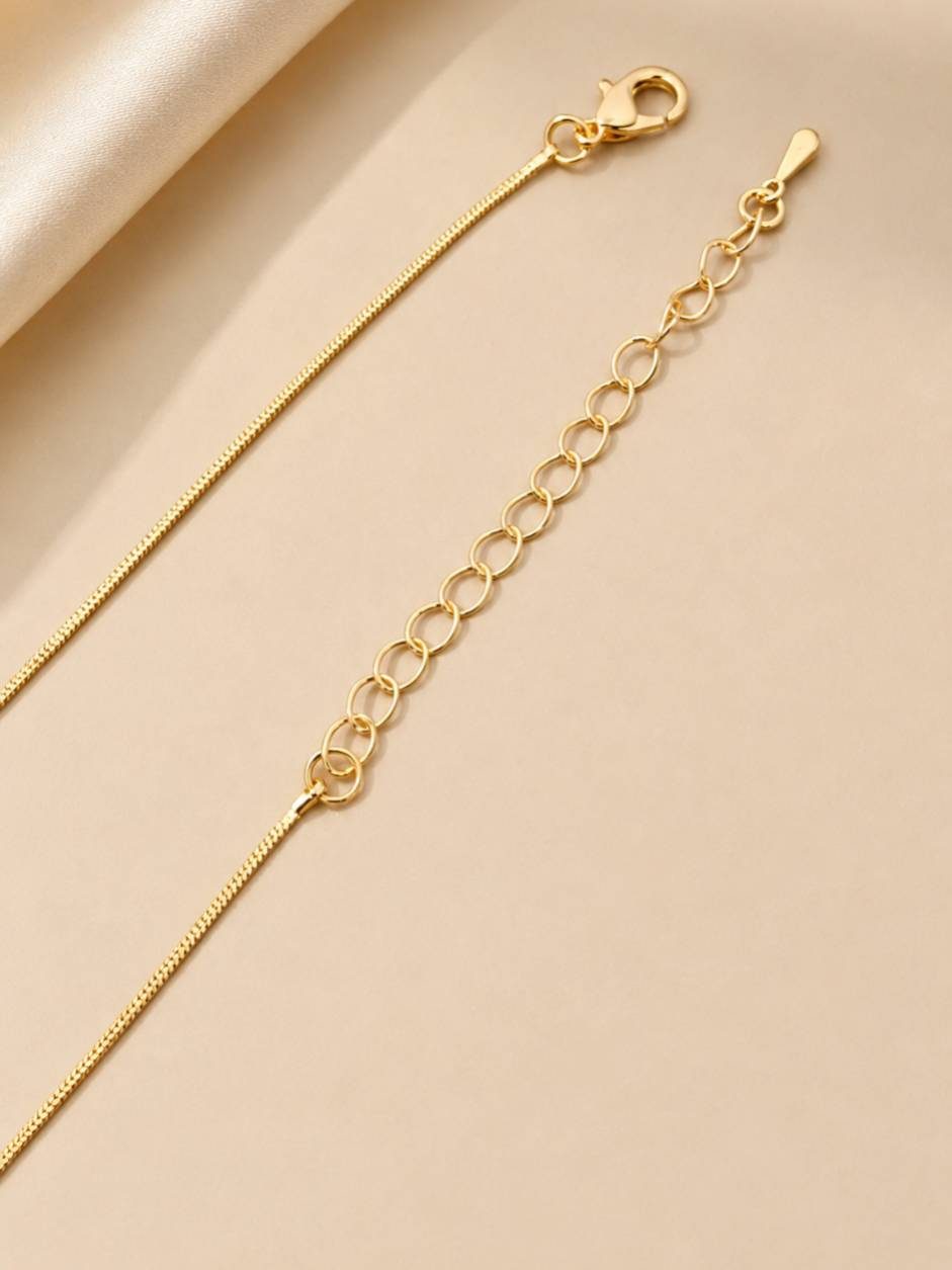 Close-up of gold snake chain showing lobster clasp and adjustable oval-link extender chain
