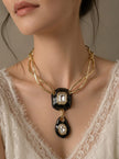Woman wearing black enamel gold-plated pendant necklace over a white lace neckline, front view