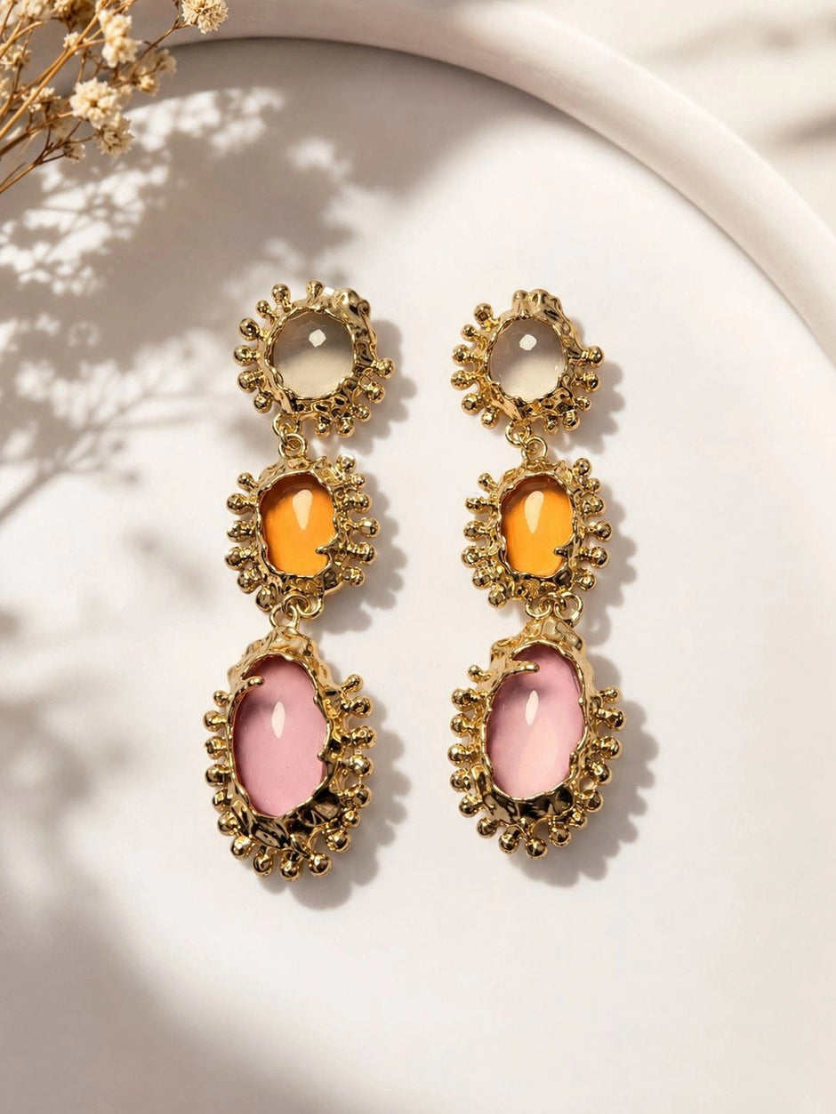 Both gold-plated triple drop earrings displayed side by side on white ceramic tray in natural light