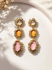 Both gold-plated triple drop earrings displayed side by side on white ceramic tray in natural light