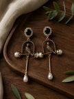 Pair of antique gold parrot cage earrings displayed on a dark wooden tray with eucalyptus leaves