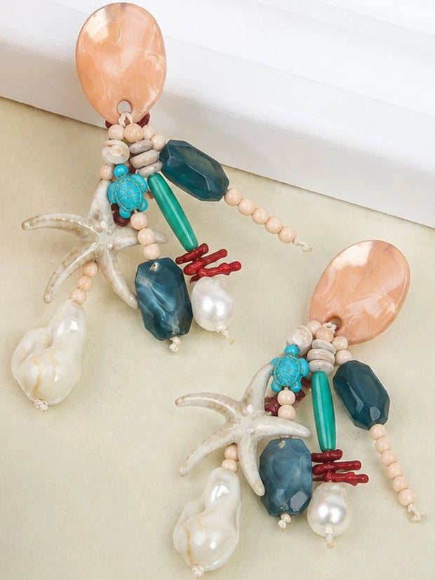 Pair of ocean beaded drop earrings flat lay showing starfish charm, turquoise turtle and baroque faux pearl