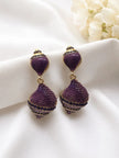 Close-up of two purple cubic zirconia two-tier drop earrings laid flat on white satin fabric