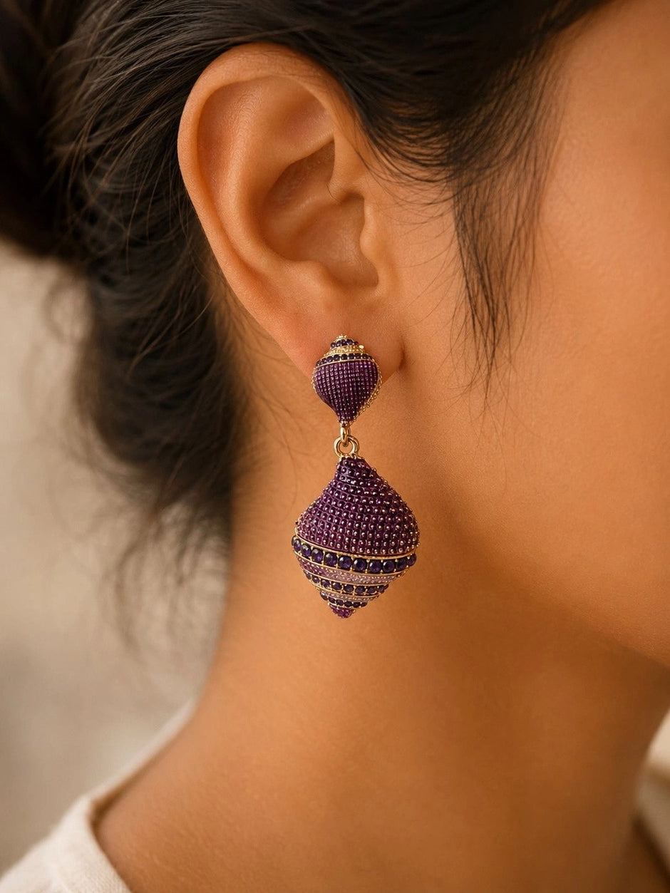 Purple geometric drop earring worn on a woman's ear showing scale and drape against warm skin