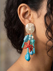 Side profile of turquoise starfish drop earring worn on a woman's ear showing full length and movement