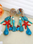 Both earrings displayed side by side against a light green background showing red starfish and turquoise bead detail