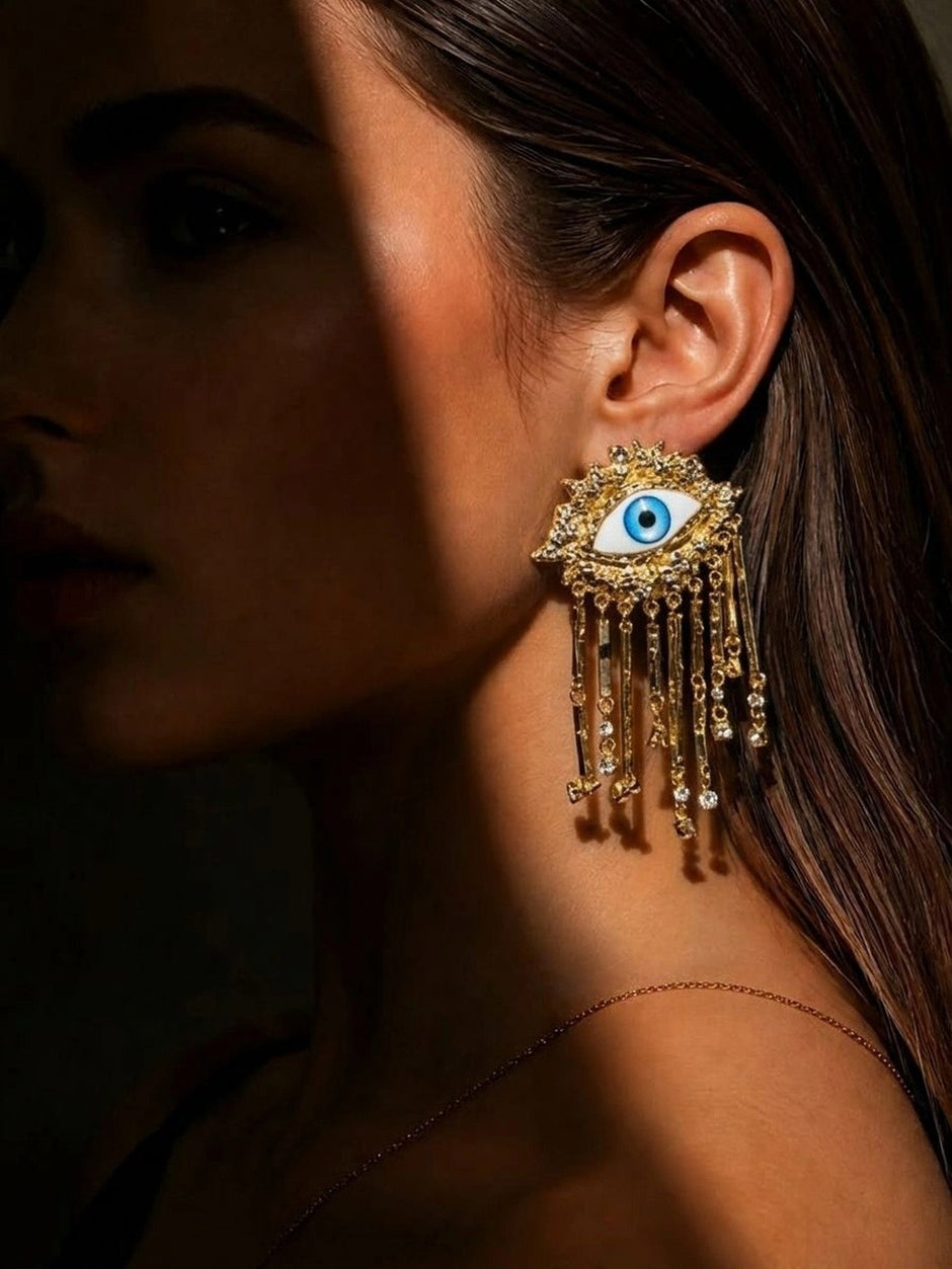 Woman wearing gold evil eye tassel drop earring showing full length and scale on ear