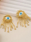 Close-up of gold evil eye tassel earrings showing rhinestone-tipped bar dangles and sunburst frame detail