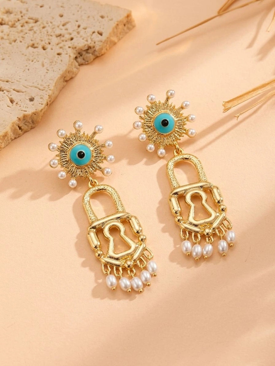 Pair of gold evil eye lock drop earrings laid flat showing turquoise enamel and pearl drops