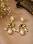 Both gold-tone evil eye pearl earrings on a dusty rose surface beside dried flowers and a vintage box