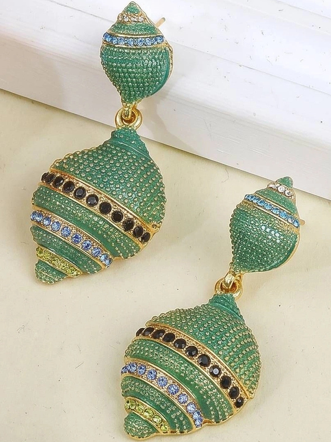 Green pavé shell drop earrings with black and blue crystal stripe details displayed on a light surface