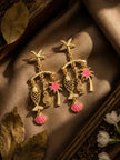 Gold-plated tropical drop earrings with pink enamel charms displayed on a dark golden fabric with leaves