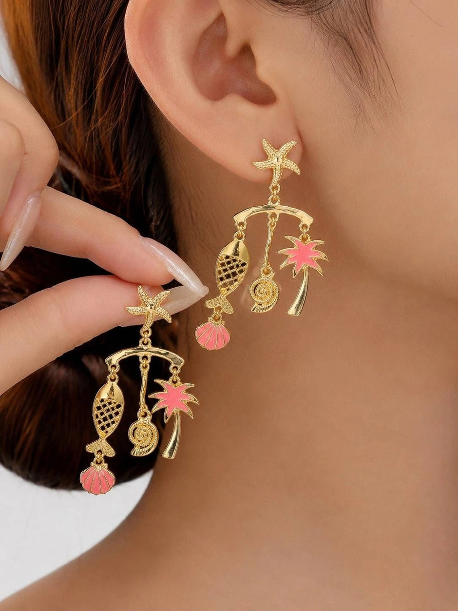 Close-up of gold tropical charm drop earring worn on a woman's ear, showing starfish stud and dangling charms