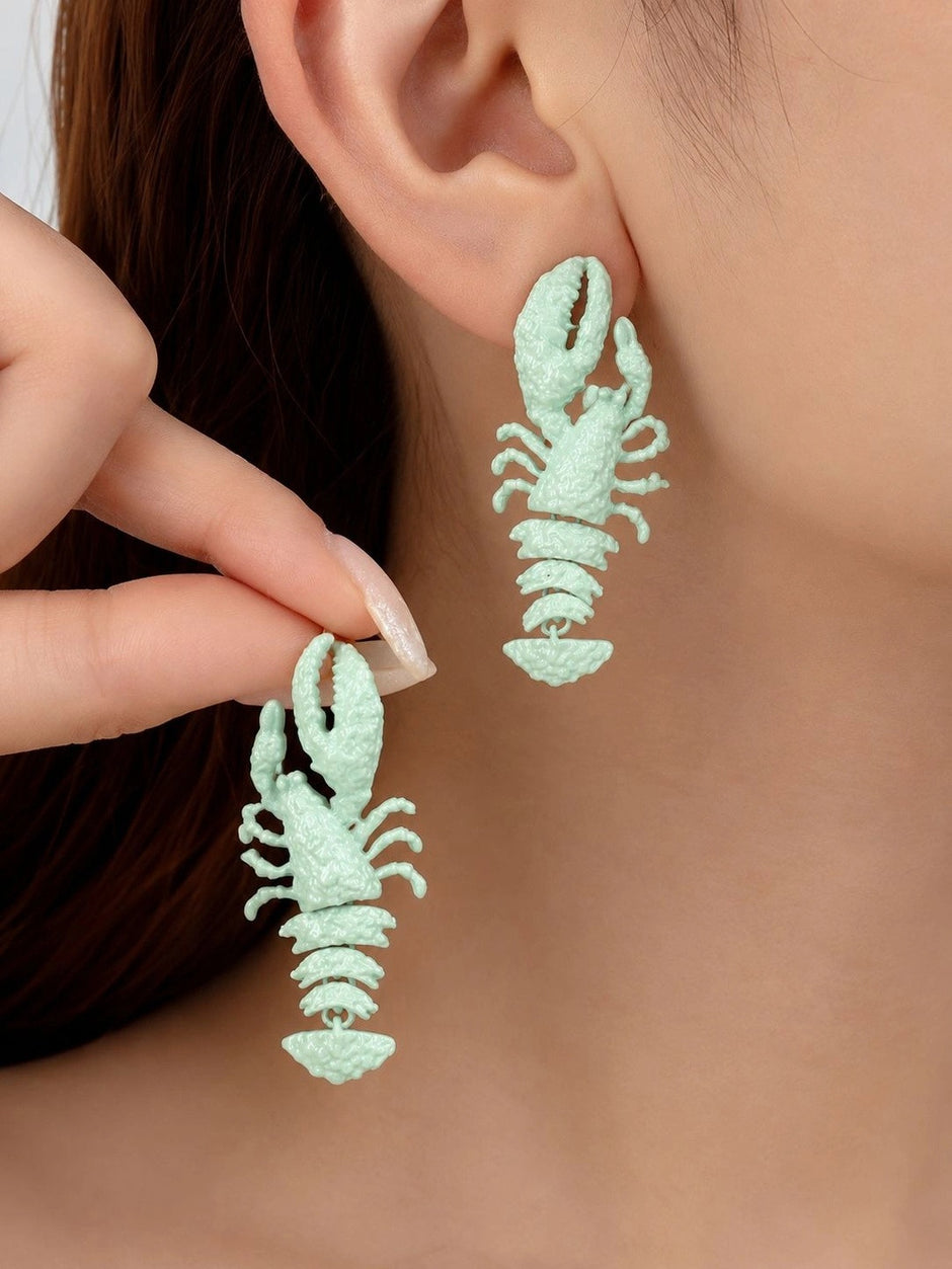 Model wearing and holding mint green lobster drop earrings close to her ear