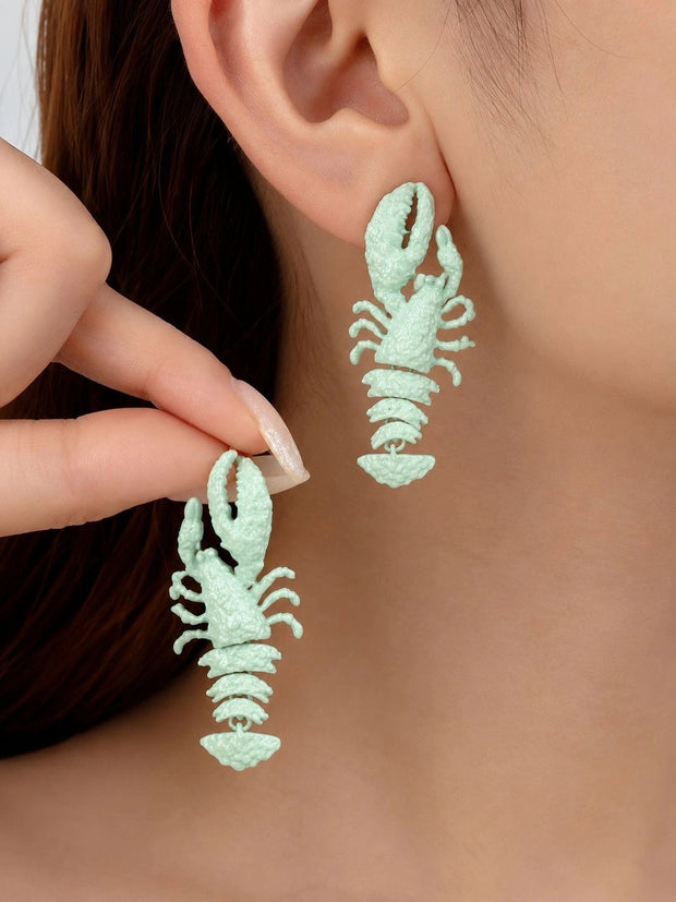 Model wearing and holding mint green lobster drop earrings close to her ear
